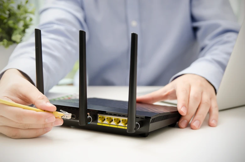 Ruka připojuje síťový kabel k Wi-Fi směrovači pro měření rychlosti.