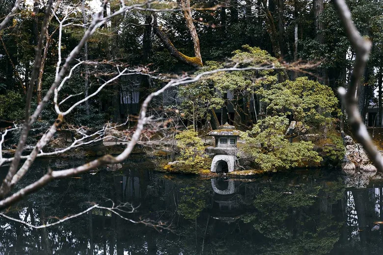 Japonská zahrada s kamenným lampionem na ostrově v jezeře.