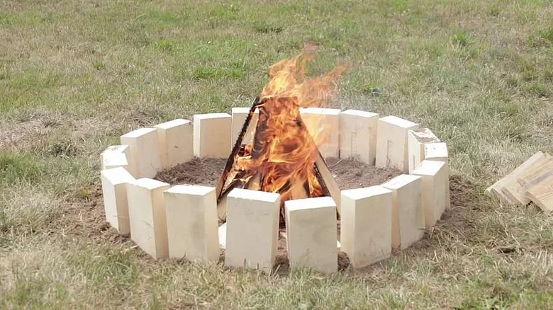 Hořící ohniště z cihel na trávě