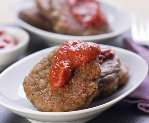 Hot houbové karbanátky s rajčatovou omáčkou na talíři.