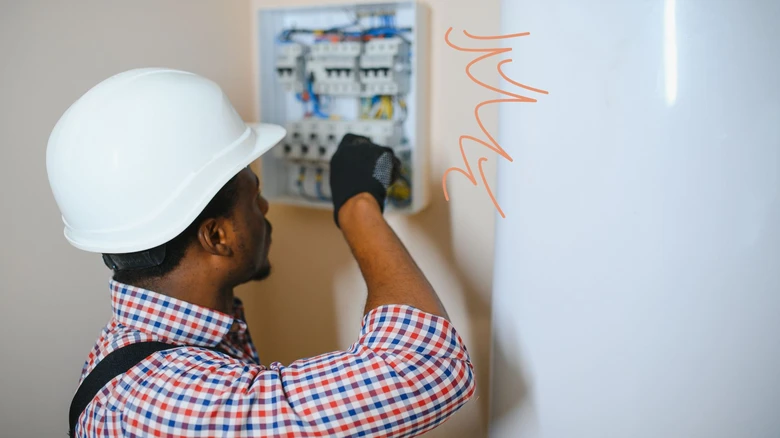 Elektrikář pracuje na rozvaděči v domovním instalaci.