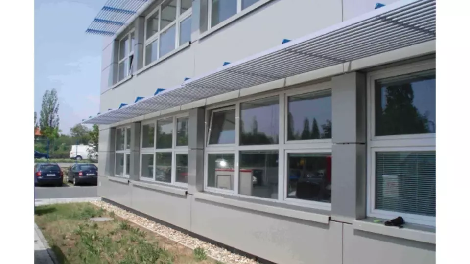 Provětrávaná fasáda s horizontálními lamelami nad okny moderní budovy.