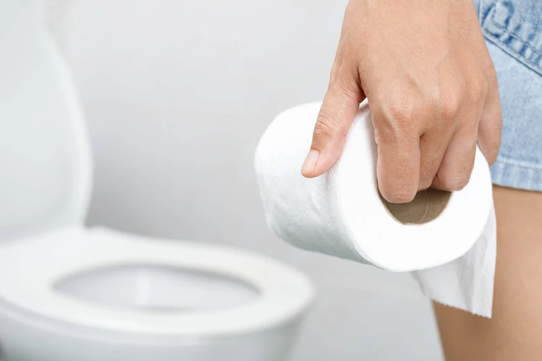 Ruka drží toaletní papír před WC