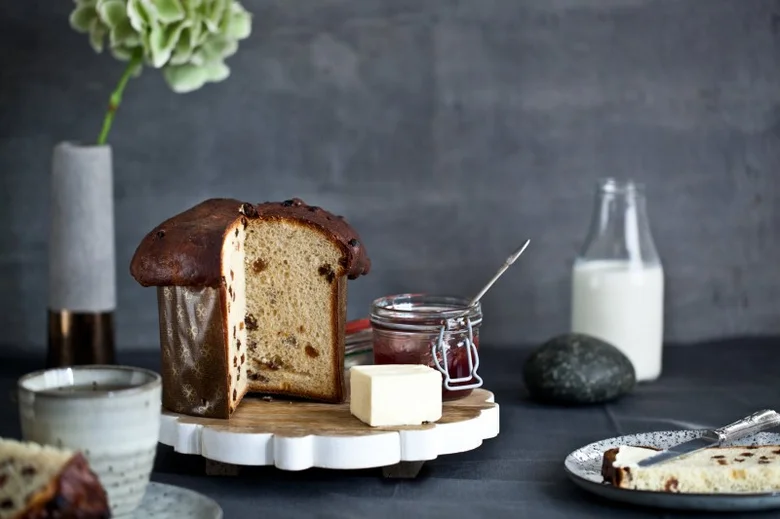 Tradiční italský koláč Panettone s rozinkami na dřevěném podnose.