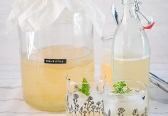 Kombucha v nádobě s filtrem a dvě skleničky připraveného nápoje.