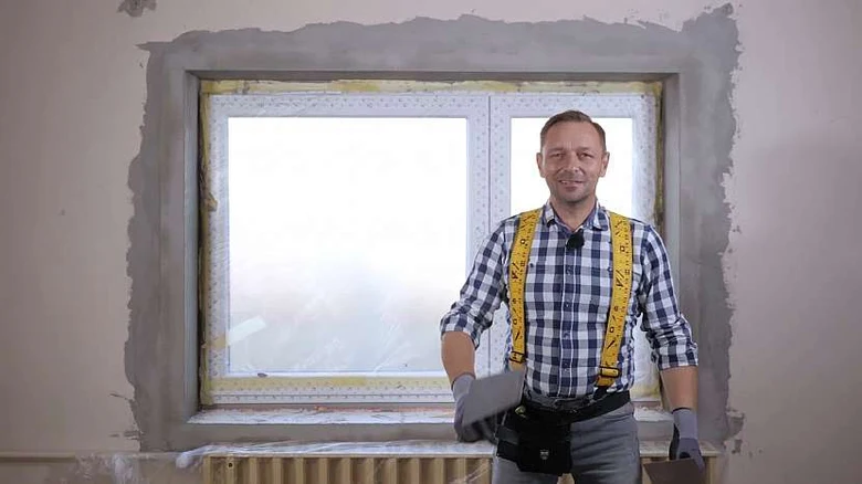 Muž při štukování okenního rámu