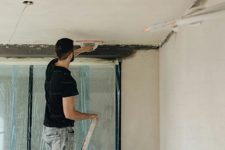 Muž při rekonstrukci bytového jádra – omítkání stropu