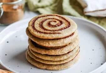 Skládané palačinky s kořením skořicí na bílém talíři.