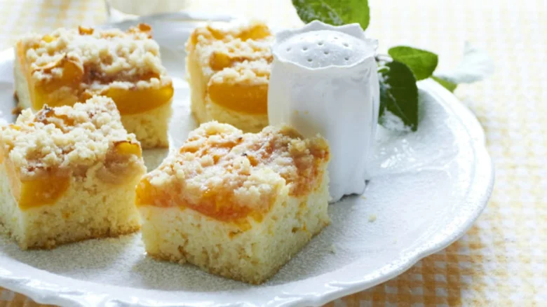 Čtyři čtvercové broskvové dezerty s krustou na bílém talíři.
