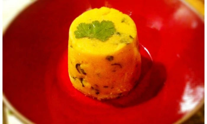 Hot polenta s garníruje čerstvou petrželkou na červeném talíři.