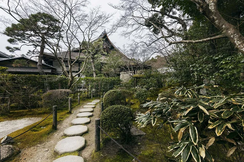 Japonská zahrada s kamennou cestou k tradičnímu domu.