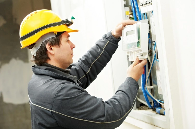 Elektrikář pracuje na rozvaděči s viditelnými kabely.