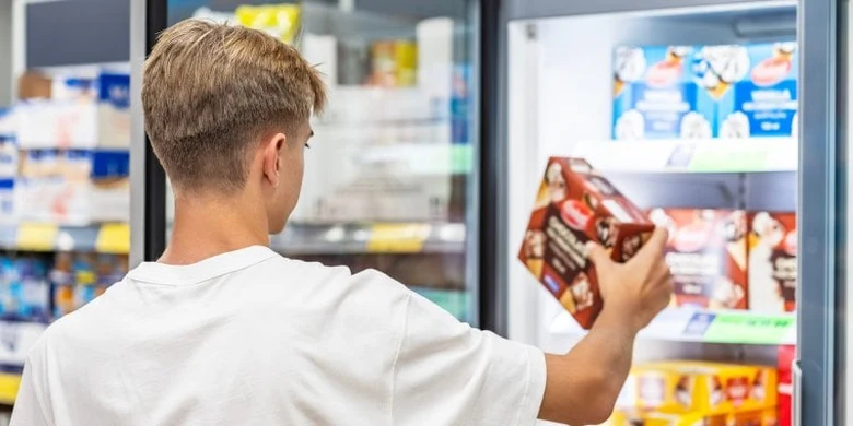 Muž vybírá zmrzlý výrobek v otevřeném obchodě