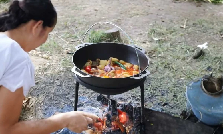 Žena vaří tradiční segedin na otevřeném ohni venku.