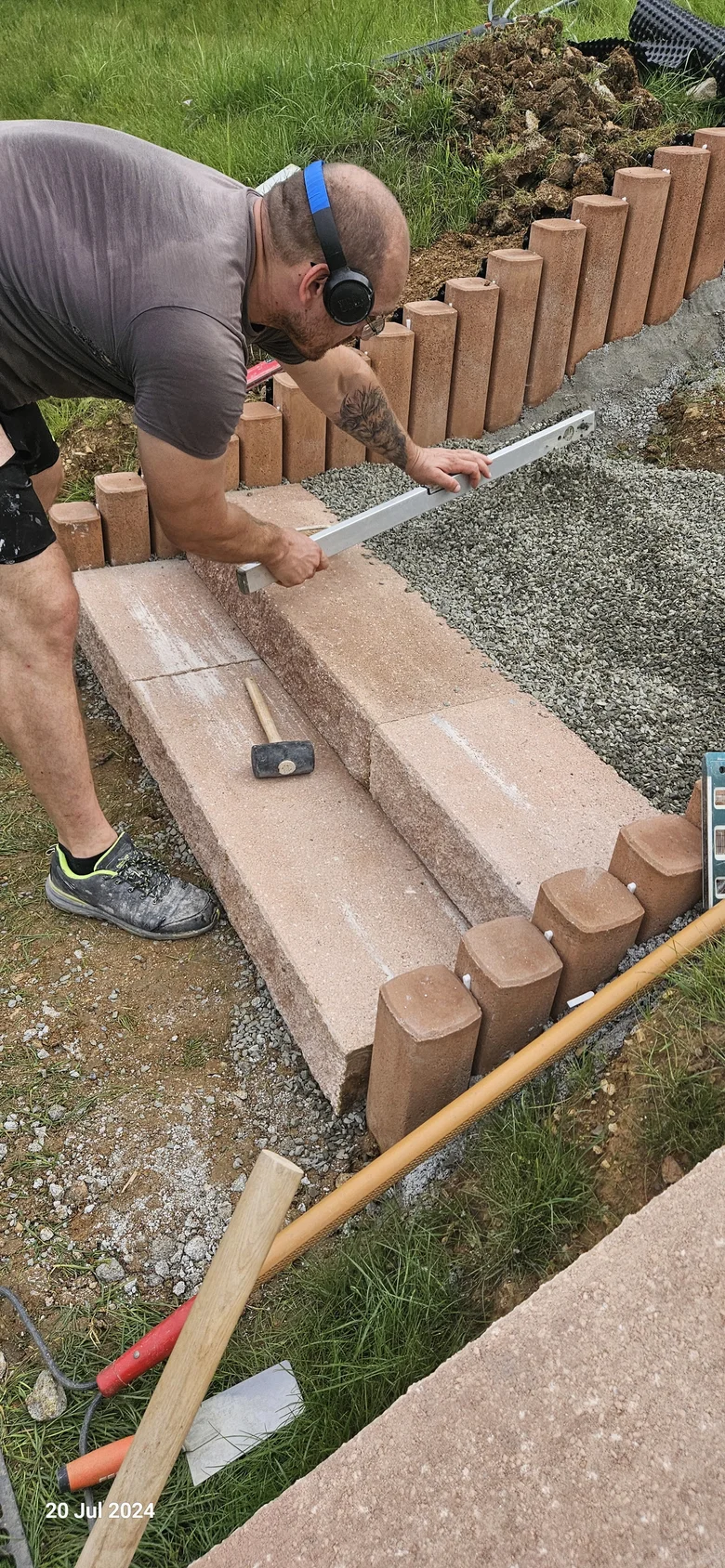 Muž staví kamenné schody na svahu
