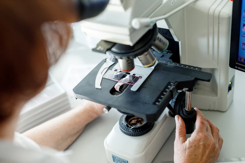 Lékař zkoumá vzorek tkáně pod mikroskopem během biopsie.