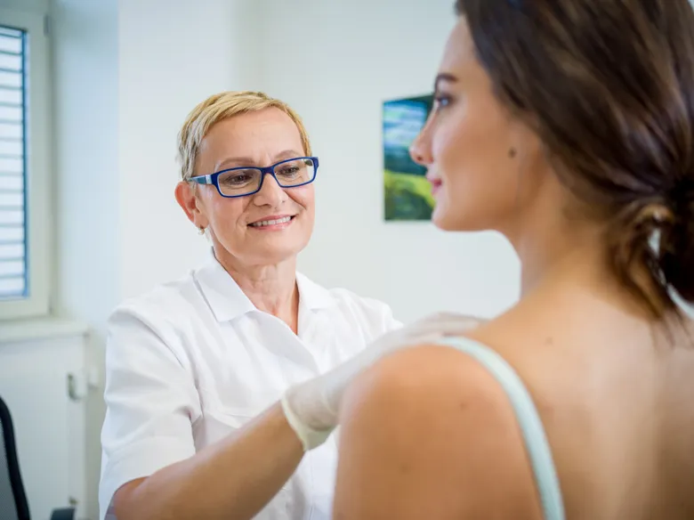 Lékařka vyšetruje pacientku při biopsii ramene.