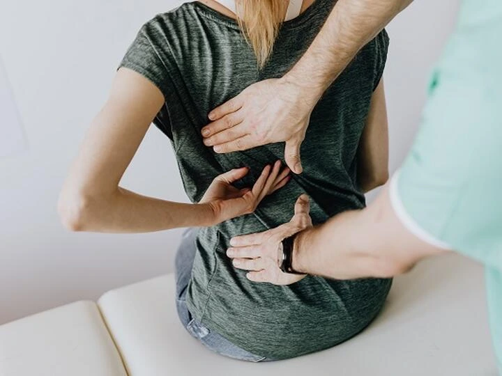 Terapeut masíruje pacientovi dolní část zad pro úlevu od bolesti.