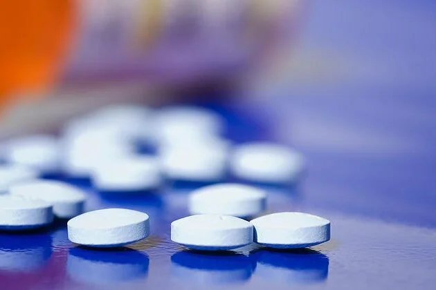Bílé tablety na modrém povrchu bez antibiotik pro léčbu.