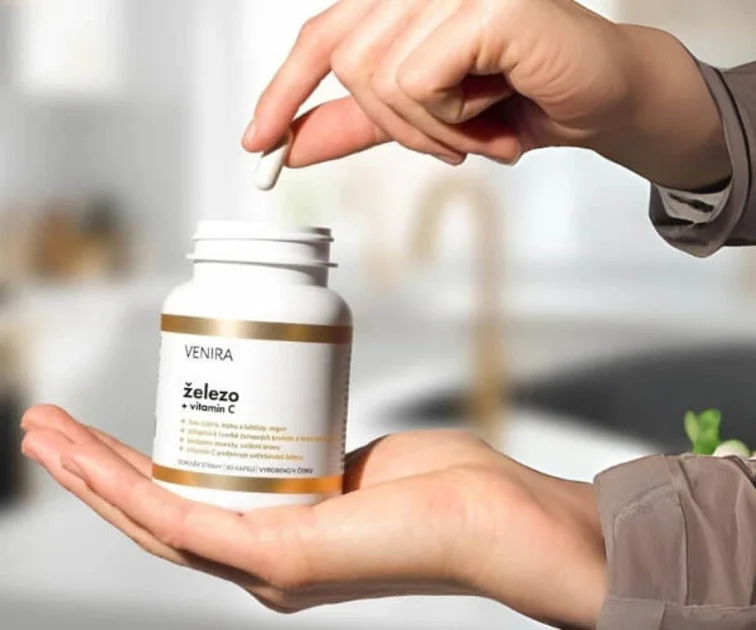 Ruka drží lahvičku železa s vitamínem C a bere tabletu.