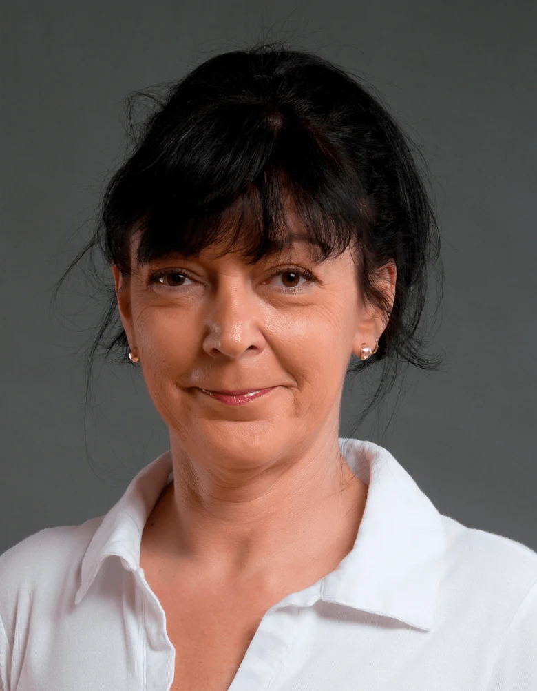 Portrét ženy v bílé košili na neutrálním pozadí.
