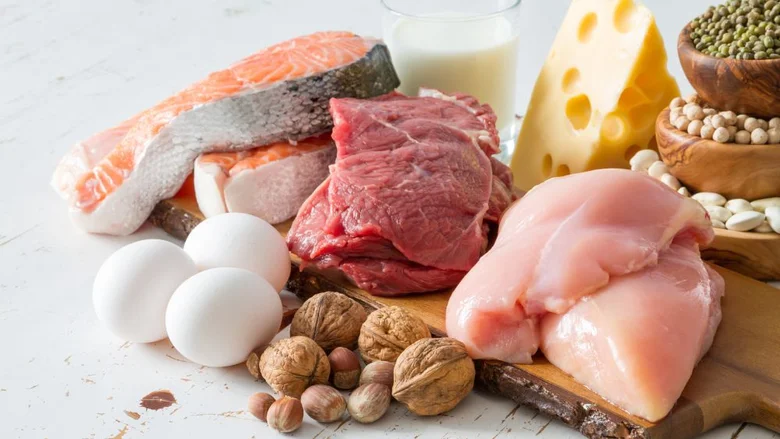Různá proteinová jídla jako ryby, maso, vejce a sýr na dřevěném talíři.
