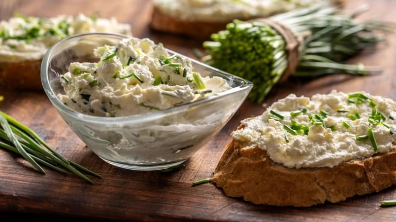 Tvarohová směs s cibulkou na kouscích toastu v dřevěné misce.