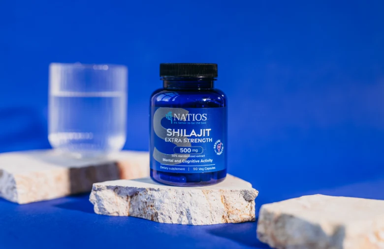 Modrá lahvička doplňku stravy shilajit na kamenném podkladu.