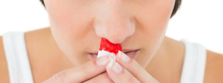 Žena s nosním krvácením používá vazelínový tampon při rýmě.