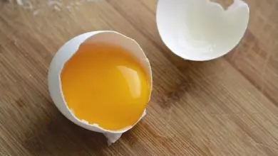 Rozbité vejce s žloutkem na dřevěném povrchu.