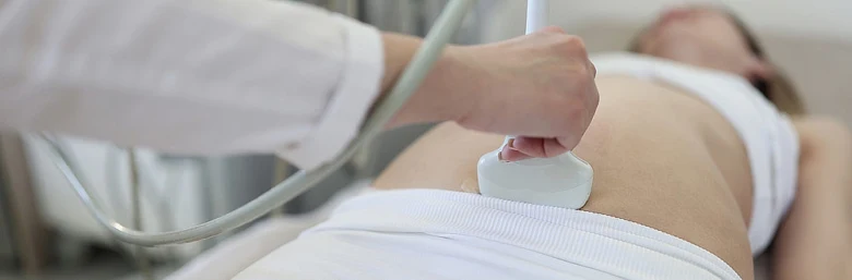 Lékař provádí ultrazvukové vyšetření břicha pacientky.