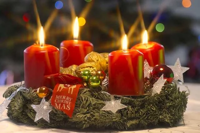 Adventní věnec se čtyřmi hořícími červenými svíčkami.