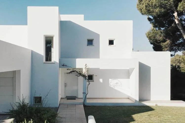 Bílý moderní minimalistický dům s geometrickými tvary a čistými liniemi.