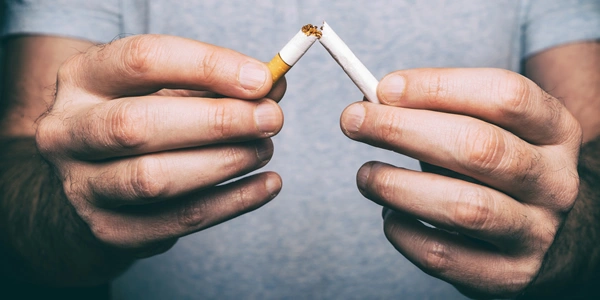 Muž láme cigaretu v rukou jako gesto přestání kouřit.