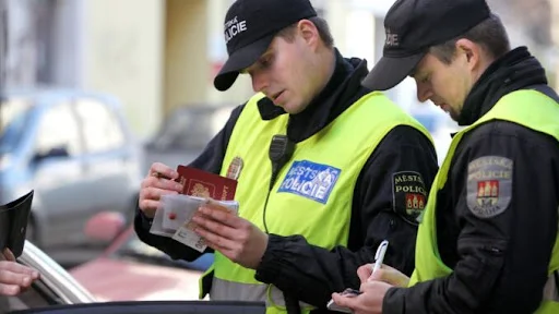 Policiisté kontrolují řidičský průkaz u auta.