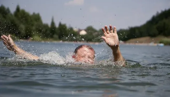 Muž se potápí ve vodě a snaží se udržet hlavu nad hladinou.