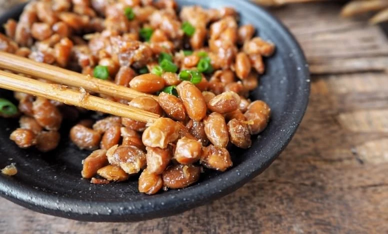 Fermentované sójové boby natto s cibulkou v černé misce.