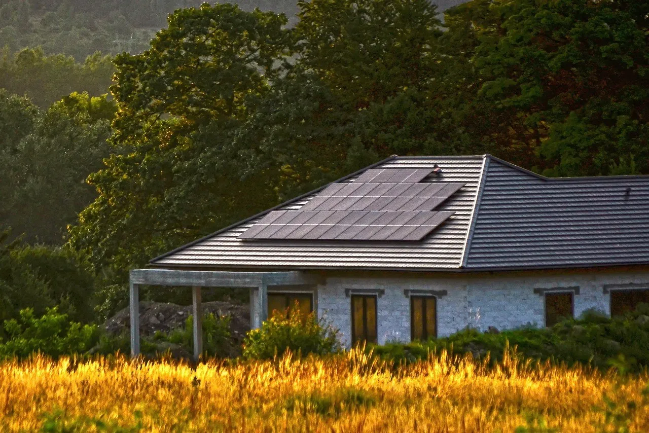 Dům s fotovoltaickými panely na střeše v přírodě.