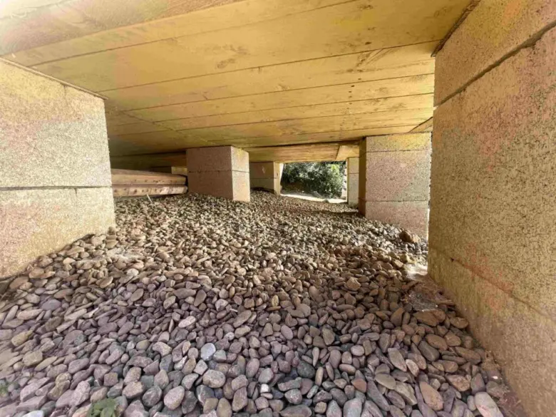 Betonové patky pod dřevostavbou s kamenivem jako základnou.
