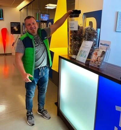 Muž v zelené vestě ukazuje na osvětlený pult s informacemi o zraku.