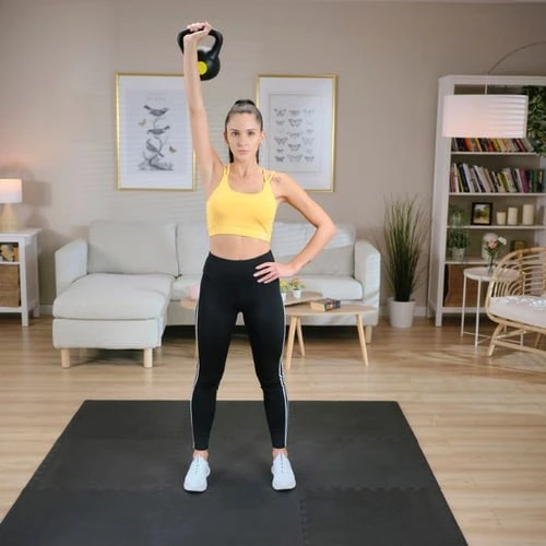 Žena dělá cvičení s kettlebellem v bytě.
