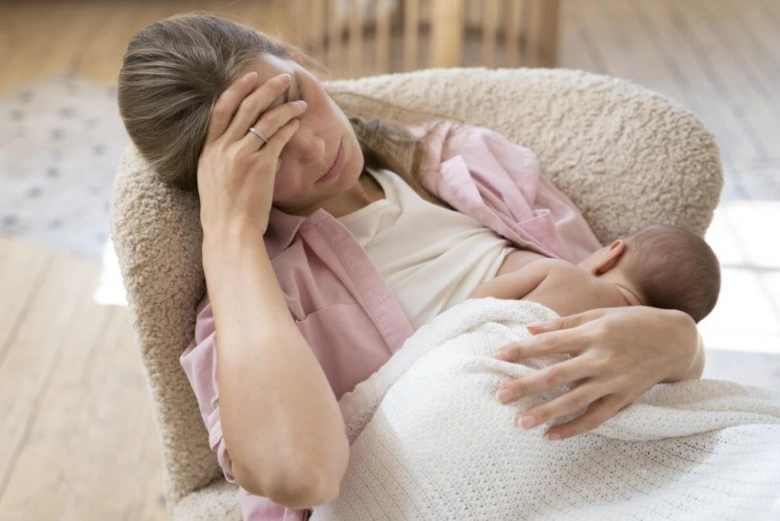 Tired mother breastfeeding baby