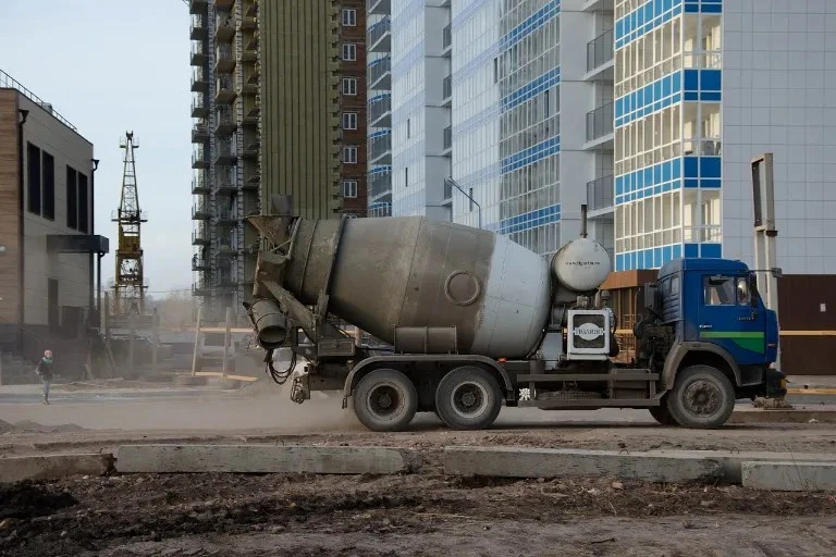 Modrý betonový míchačka stojí na staveništi u novostaveb.