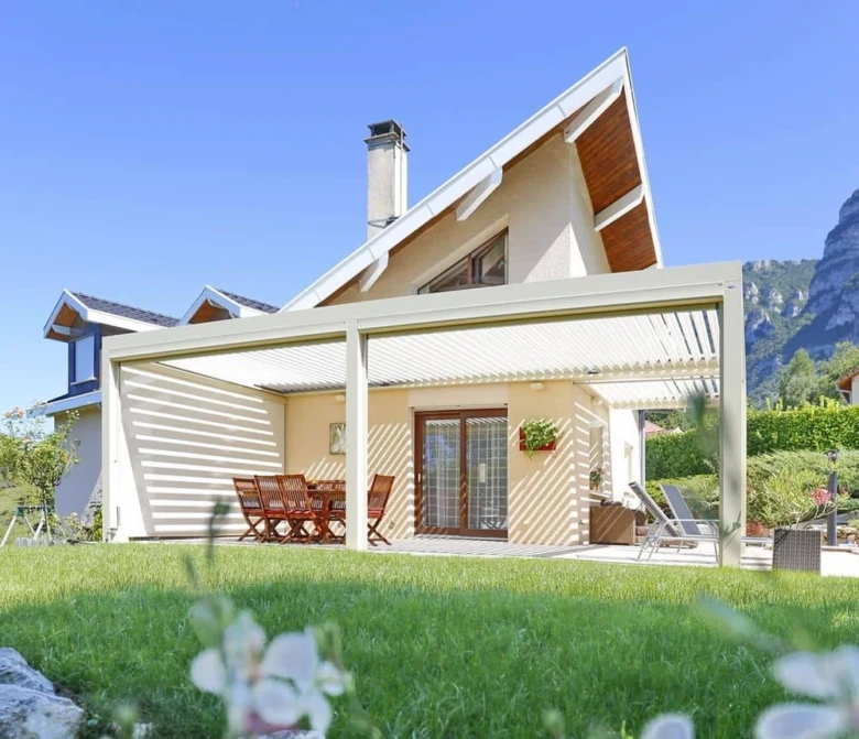 Moderní bílá zahradní pergola s dřevěným nábytkem na trávníku.