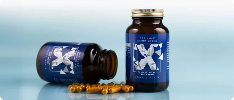 Fialová lahvička s vitamínem pro muže leží vedle stojící lahvinky.