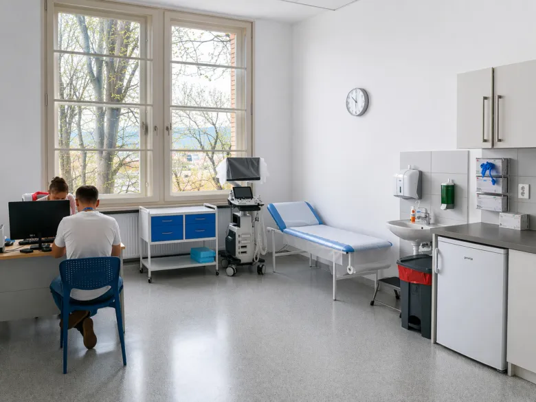 Vnitřek ordinace urologa s lůžkem a diagnostickým zařízením.