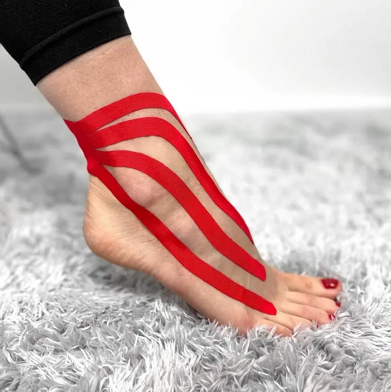 Červená kinéziotape na kotníku pro léčbu bolesti.