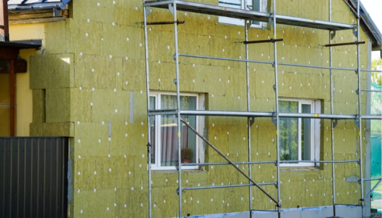 Žlutá izolace fasády domu s opěrným schodištěm pro vlastní tepelnou úpravu.