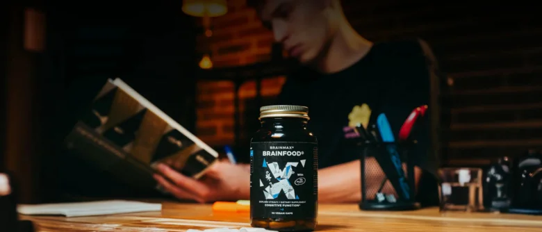 Doplňkový prostředek Brainfood na dřevěném stole s osobou v pozadí.