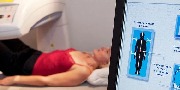 Žena v CT přístroji s obrazovkou ukazující lidské tělo.